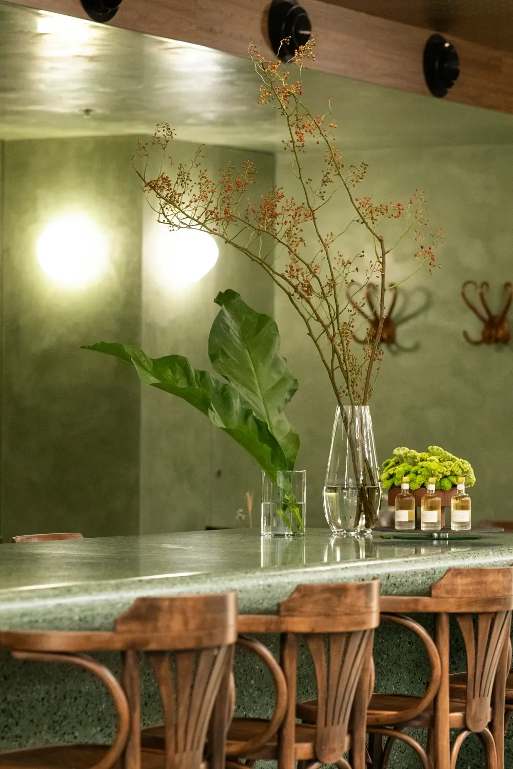 A bar with chairs and a vase of flowers on it.