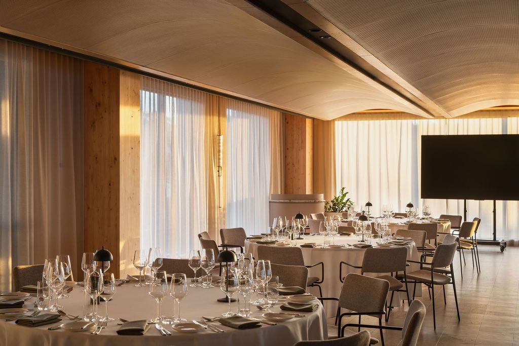 A white building with arched windows and potted plants in front of it.