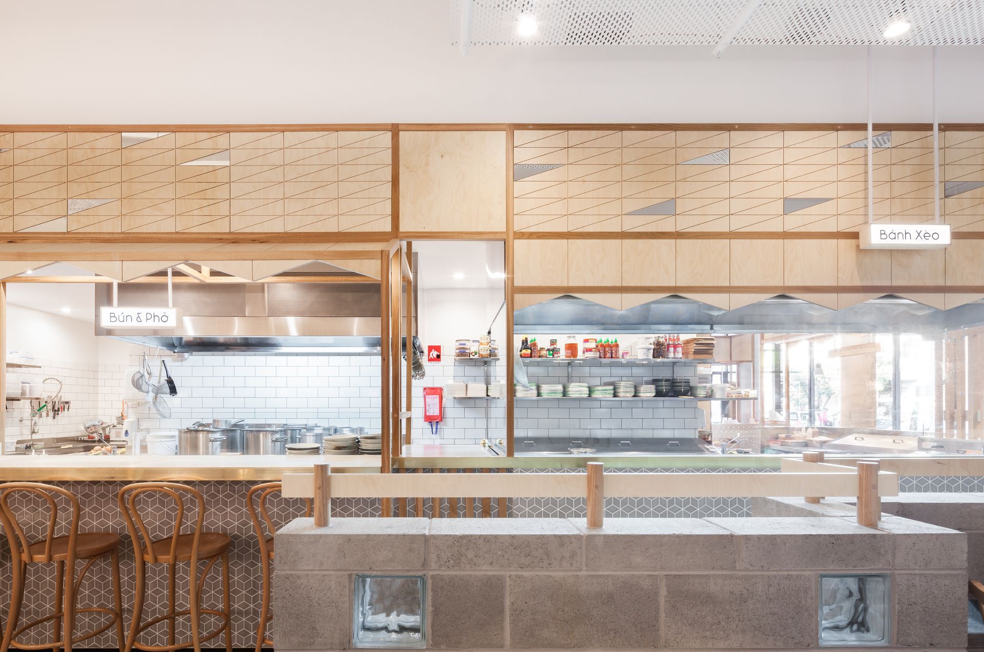 A kitchen with a counter and stools in a restaurant.