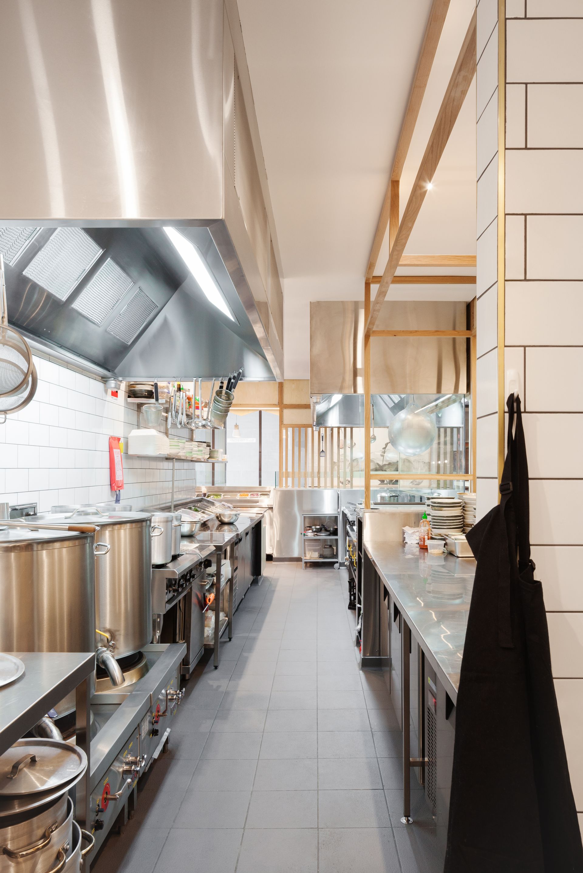 A long kitchen with stainless steel appliances and pots and pans.