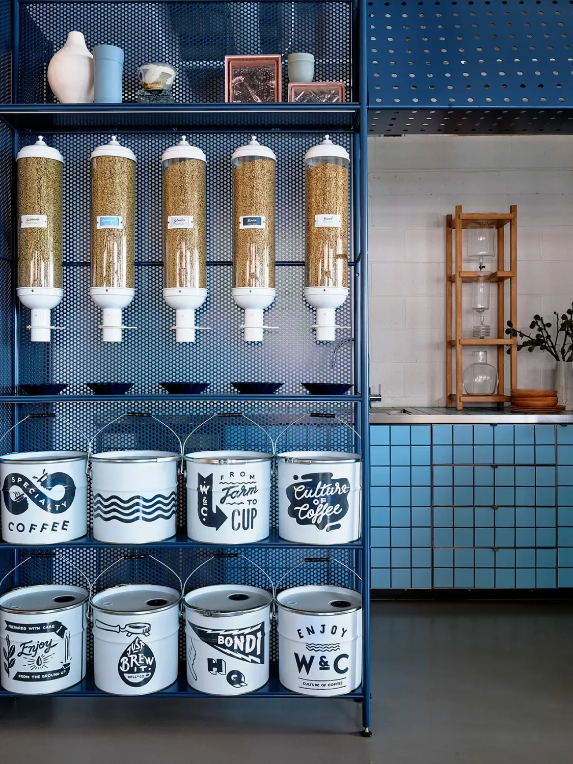A shelf filled with buckets and containers in a kitchen.