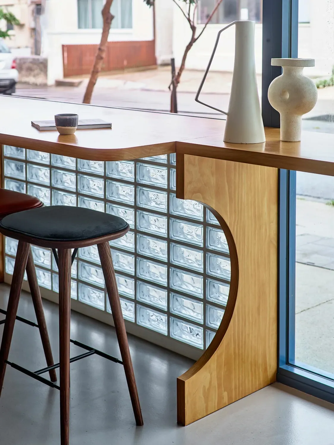 A wooden table with two stools in front of a window.