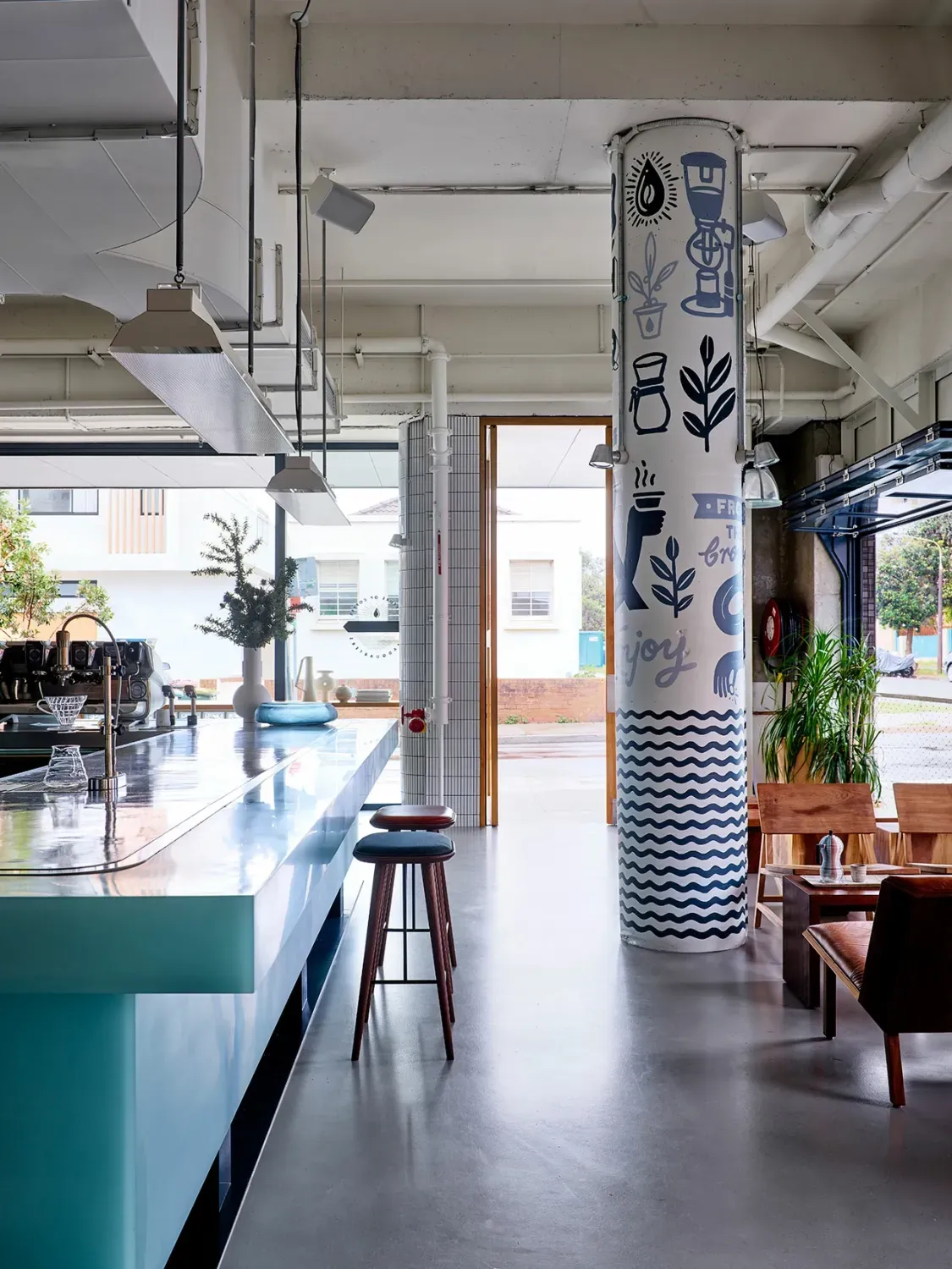 A restaurant with a bar and stools and a pillar with drawings on it.