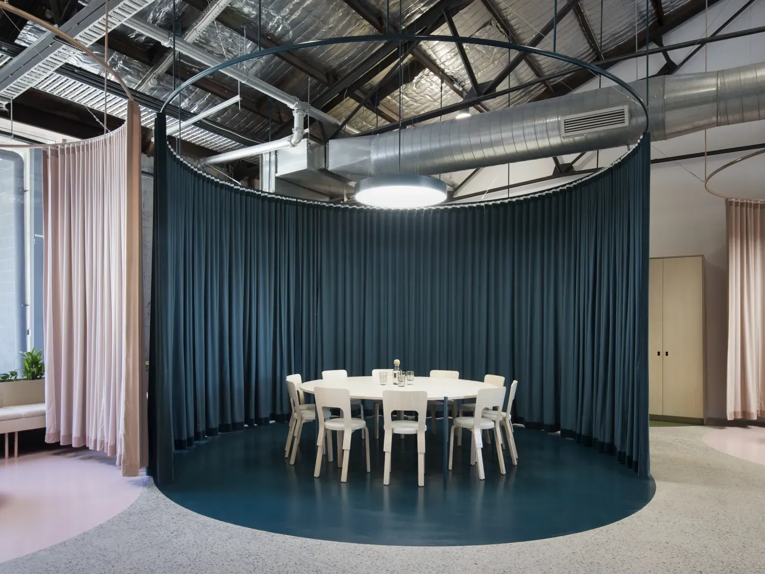 A round table and chairs in a room with blue curtains.