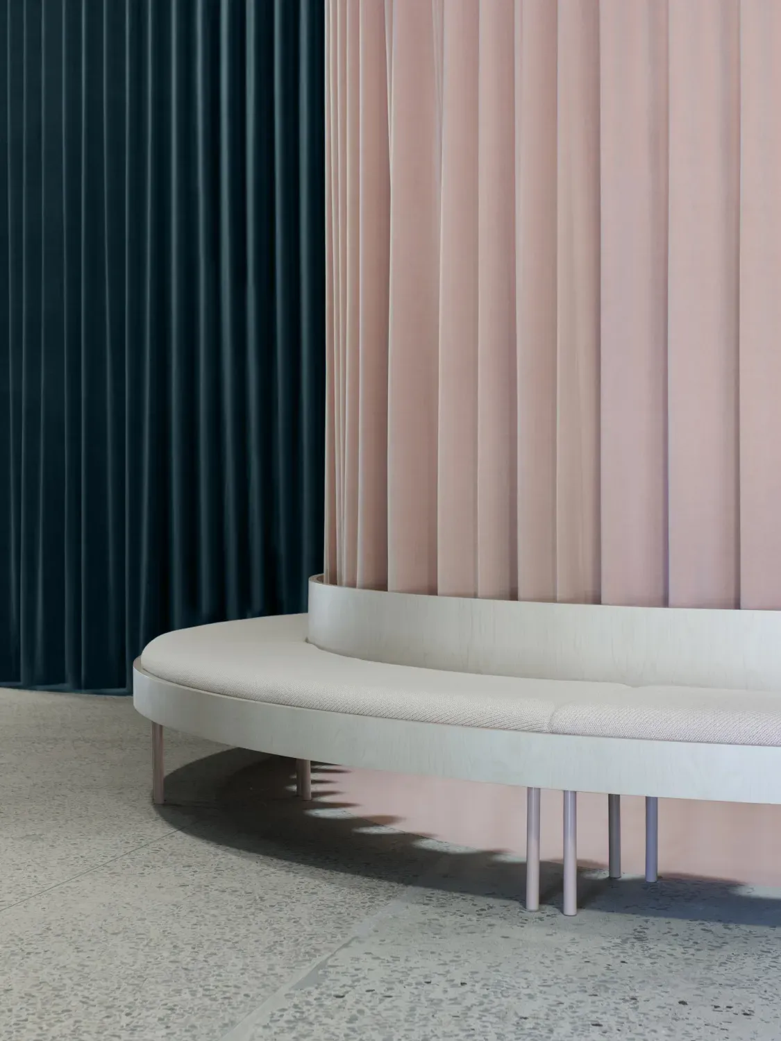 A white bench is sitting in front of a pink wall.