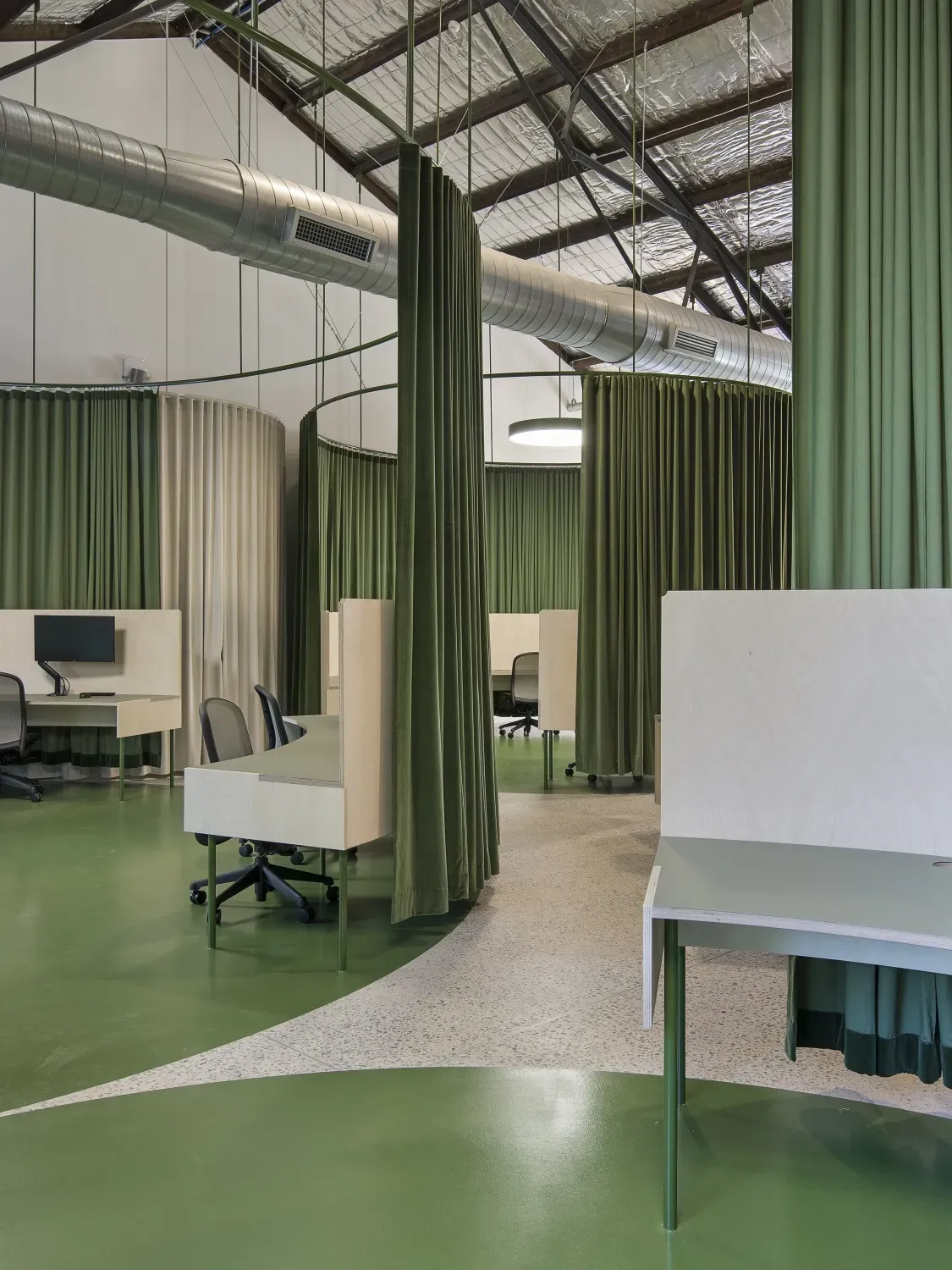 A large room with green curtains and tables and chairs.
