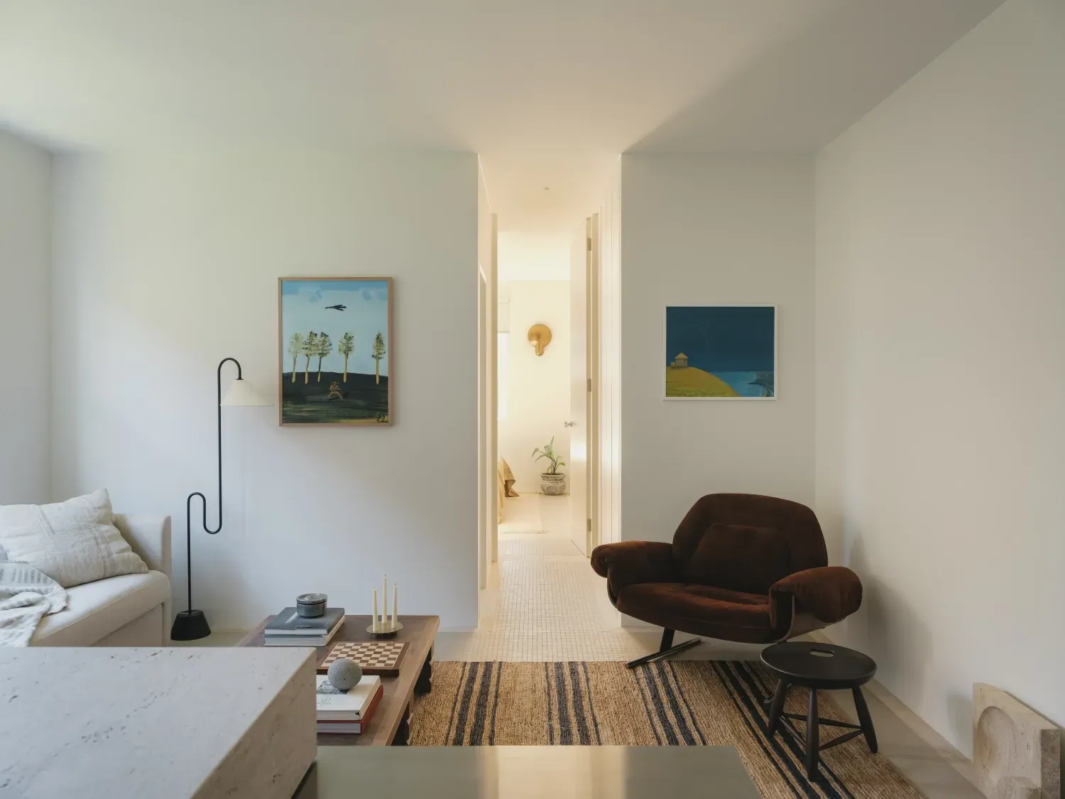 A living room with a couch , chair , table and painting on the wall.