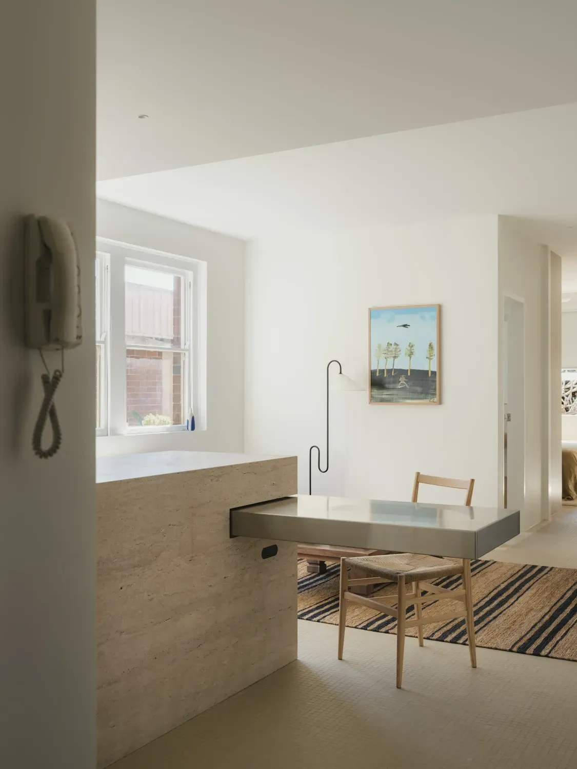 A living room with a table and chairs and a phone on the wall