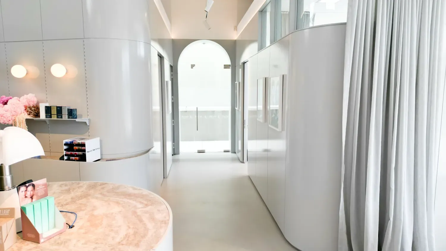 A long hallway with a table and a lamp in the middle of it.