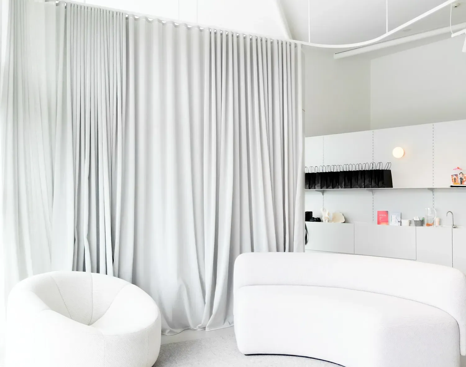A white room with white curtains and a white chair.