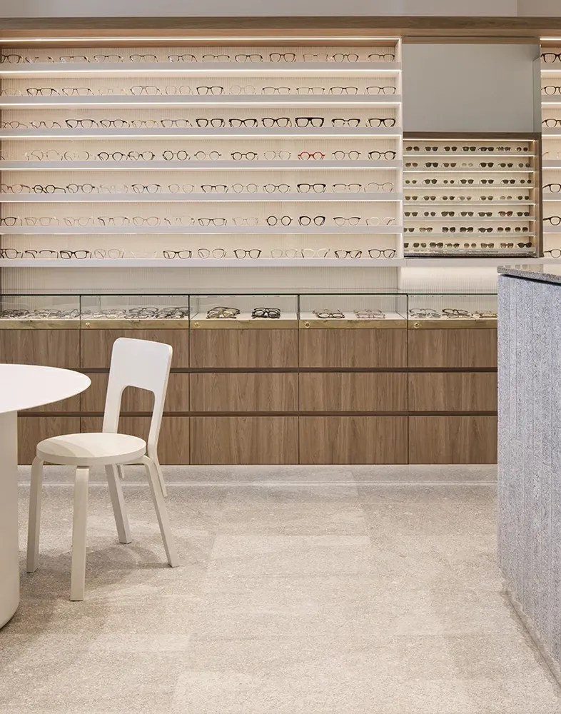 A chair is sitting in a room with a table and shelves filled with glasses.