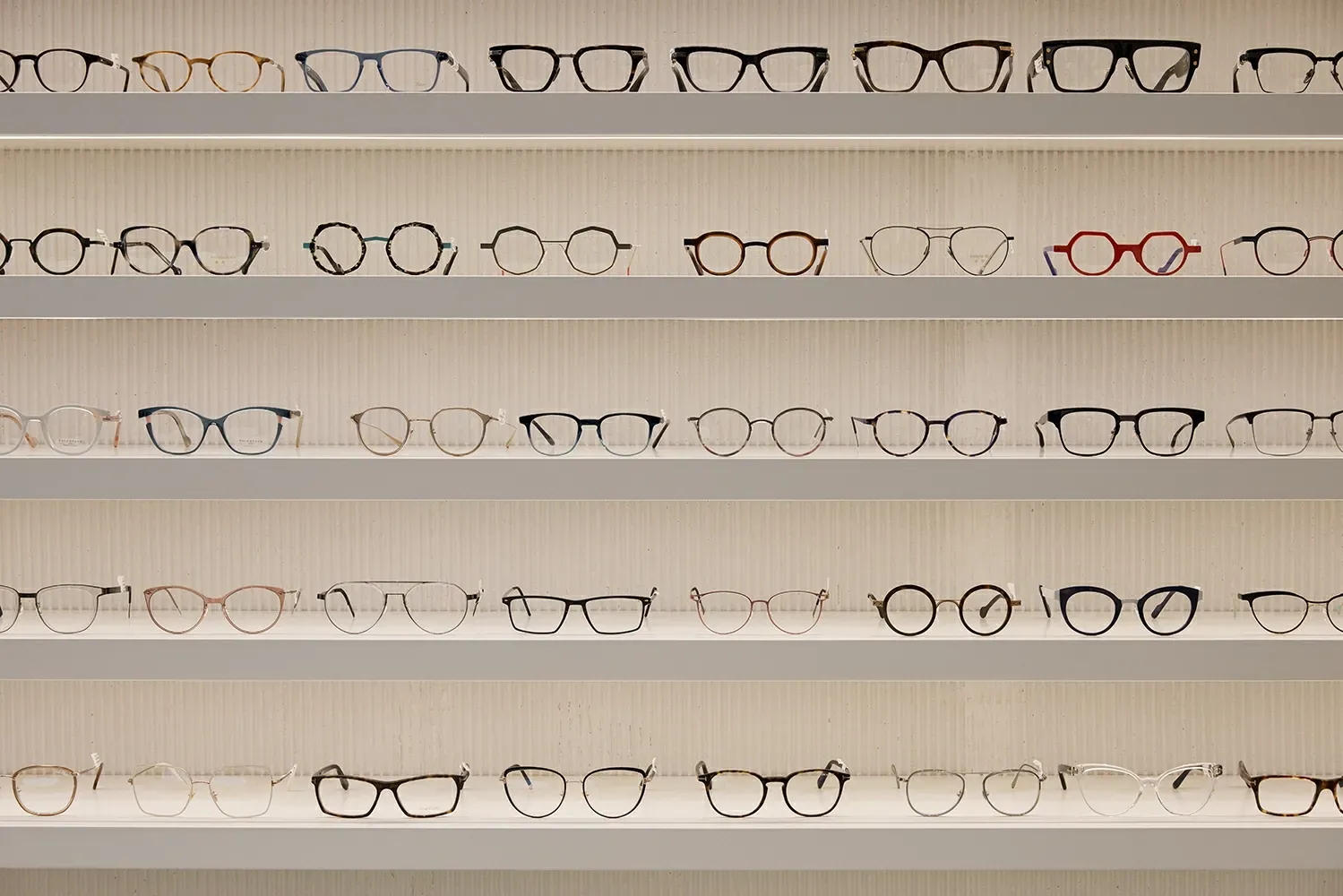 There are many different types of glasses on the shelves.