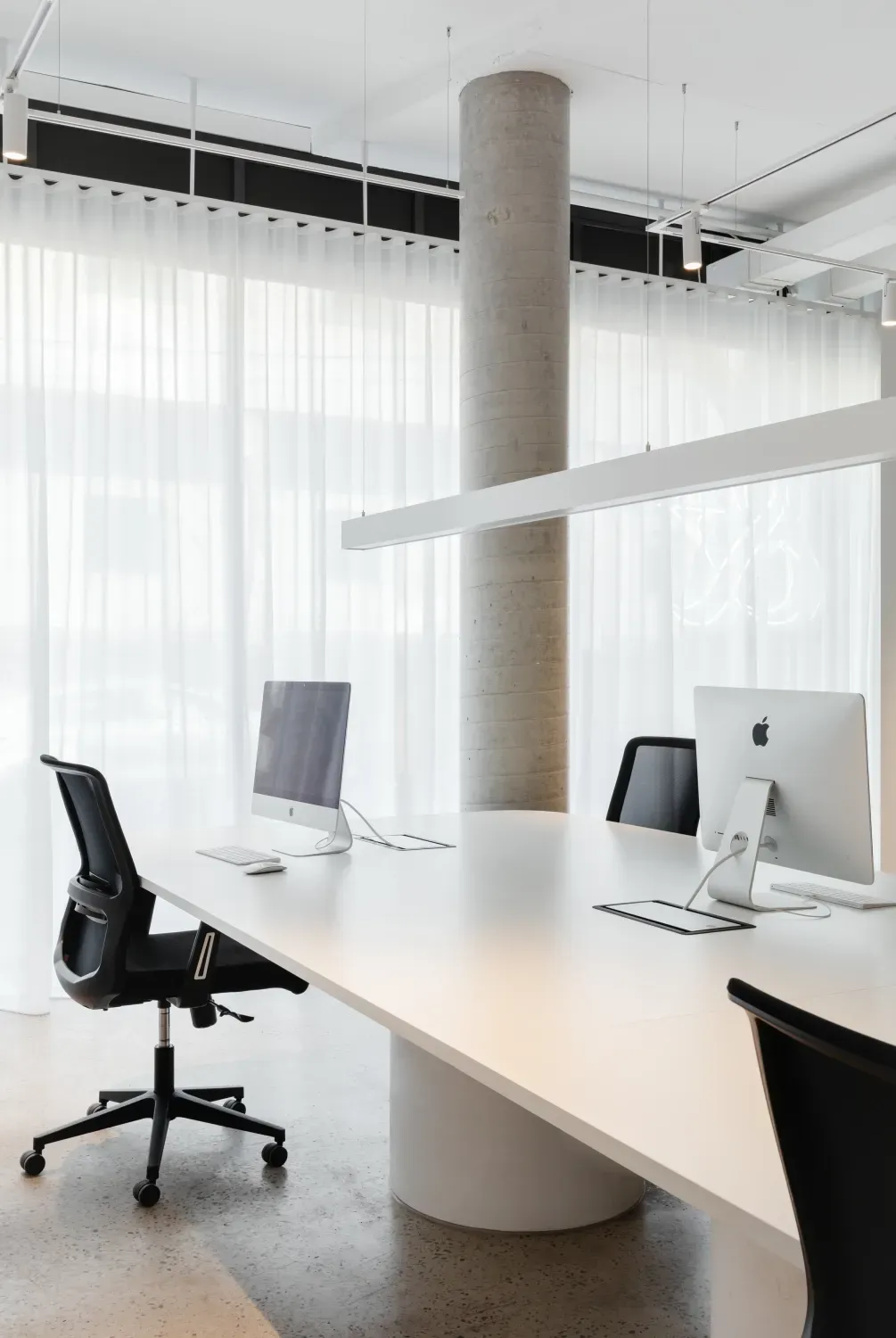 A conference room with a long white table and two computer monitors on it.