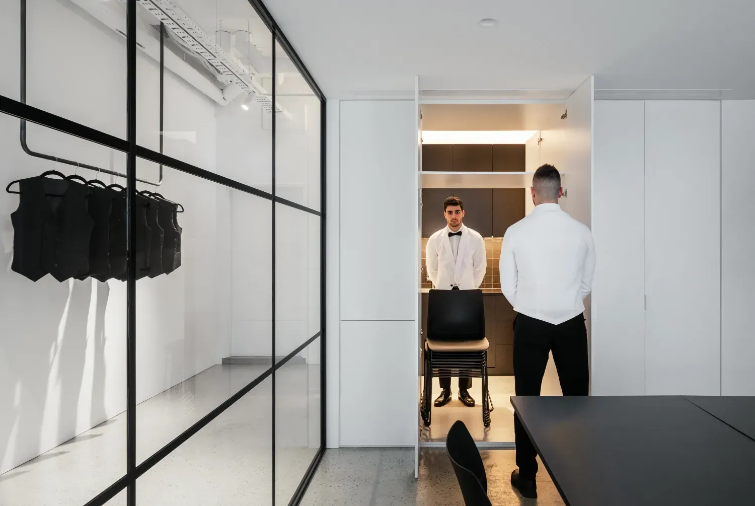 Two men are standing in a room with a glass wall.