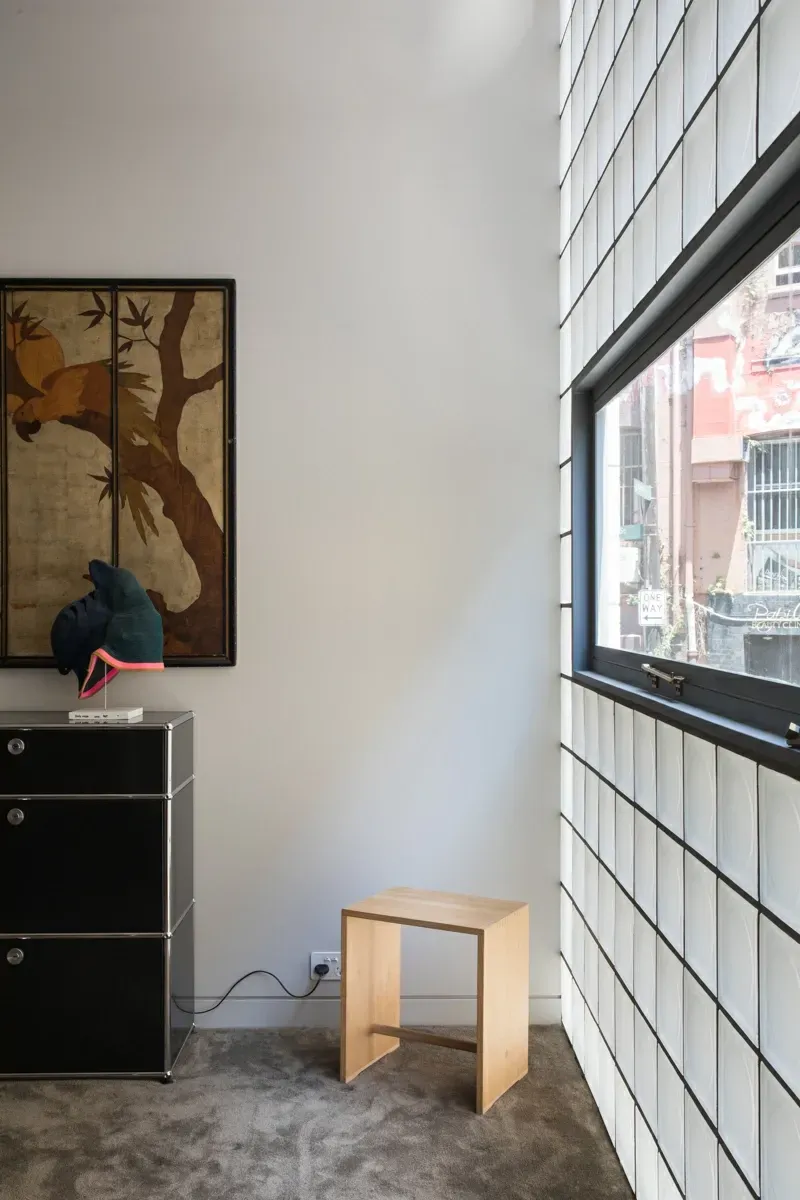 A room with a wooden stool and a picture on the wall.
