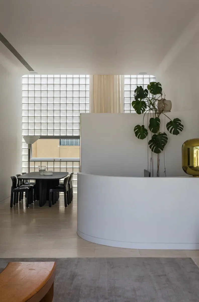 A living room with a table and chairs and a plant on the wall.