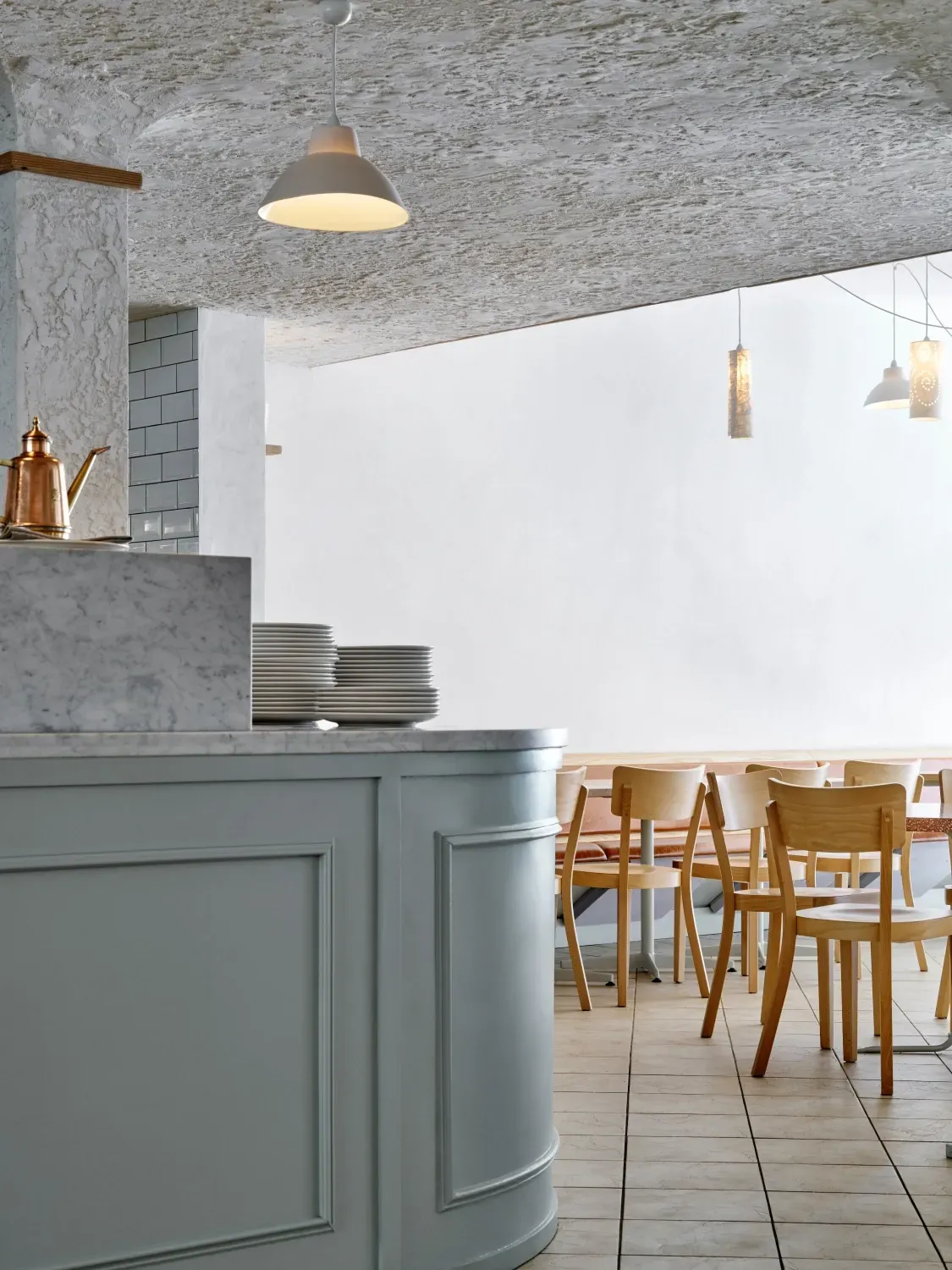 A restaurant with tables and chairs and plates on the counter