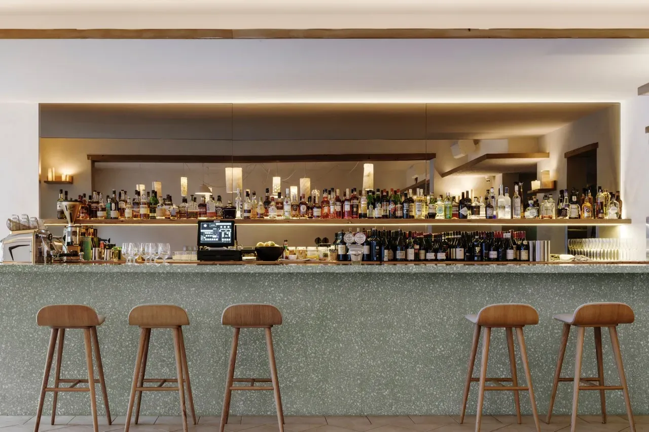 A bar with a lot of bottles on it and stools.