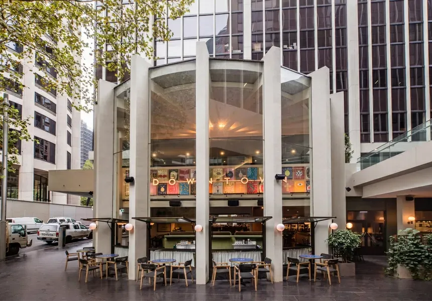 A large building with tables and chairs in front of it.