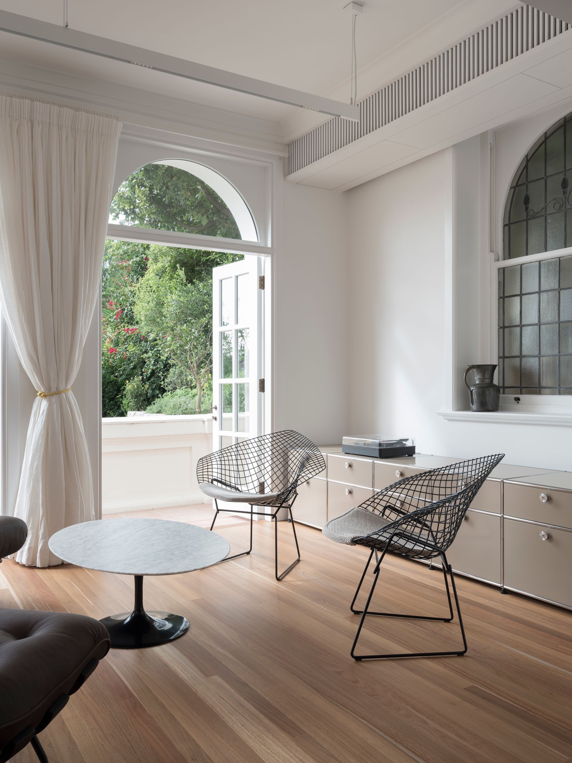 A living room with a table , chairs , and a large window.