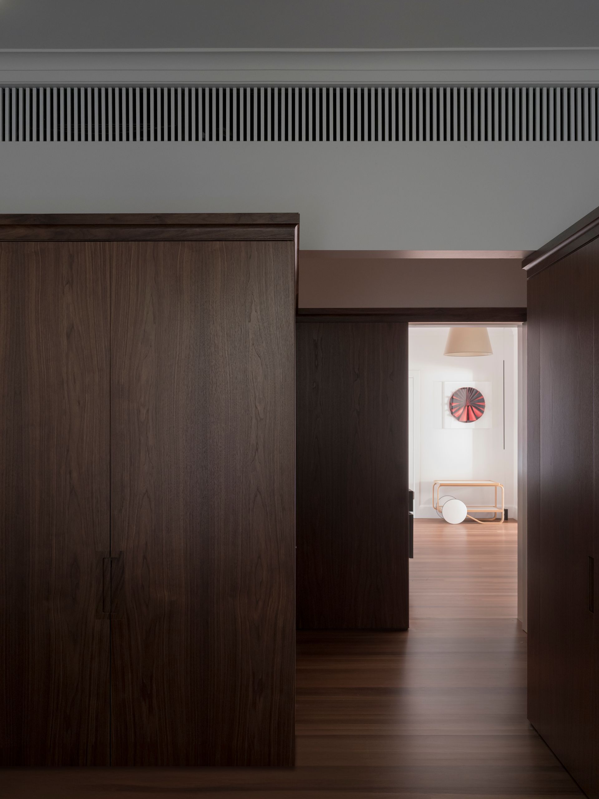 A hallway with wooden walls and sliding doors leading to a living room.