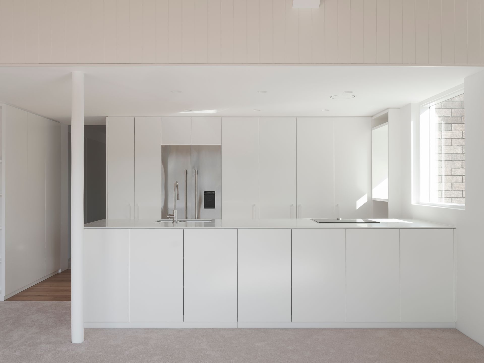 A kitchen with white cabinets , a refrigerator and a sink.