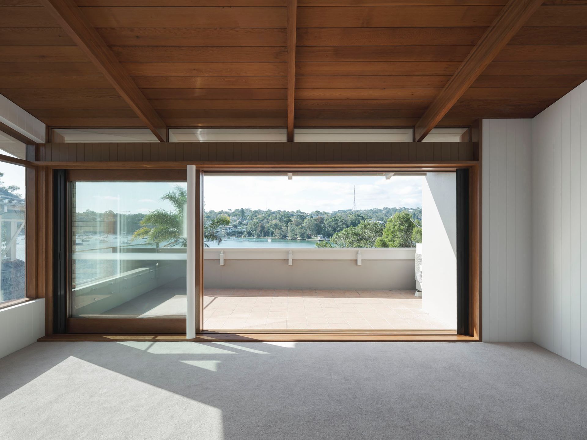 An empty room with a sliding glass door leading to a balcony