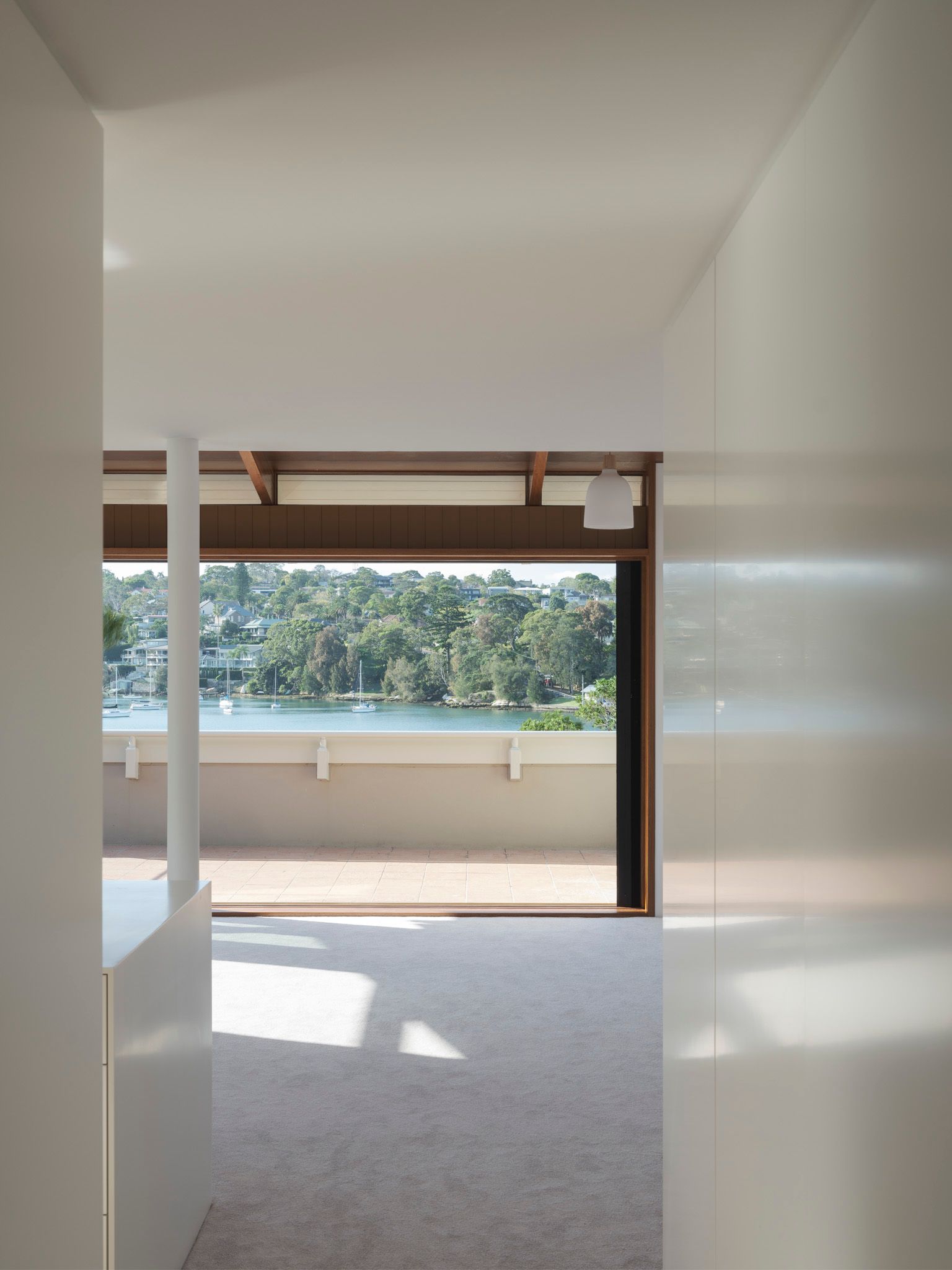 A hallway leading to a balcony with a view of a lake