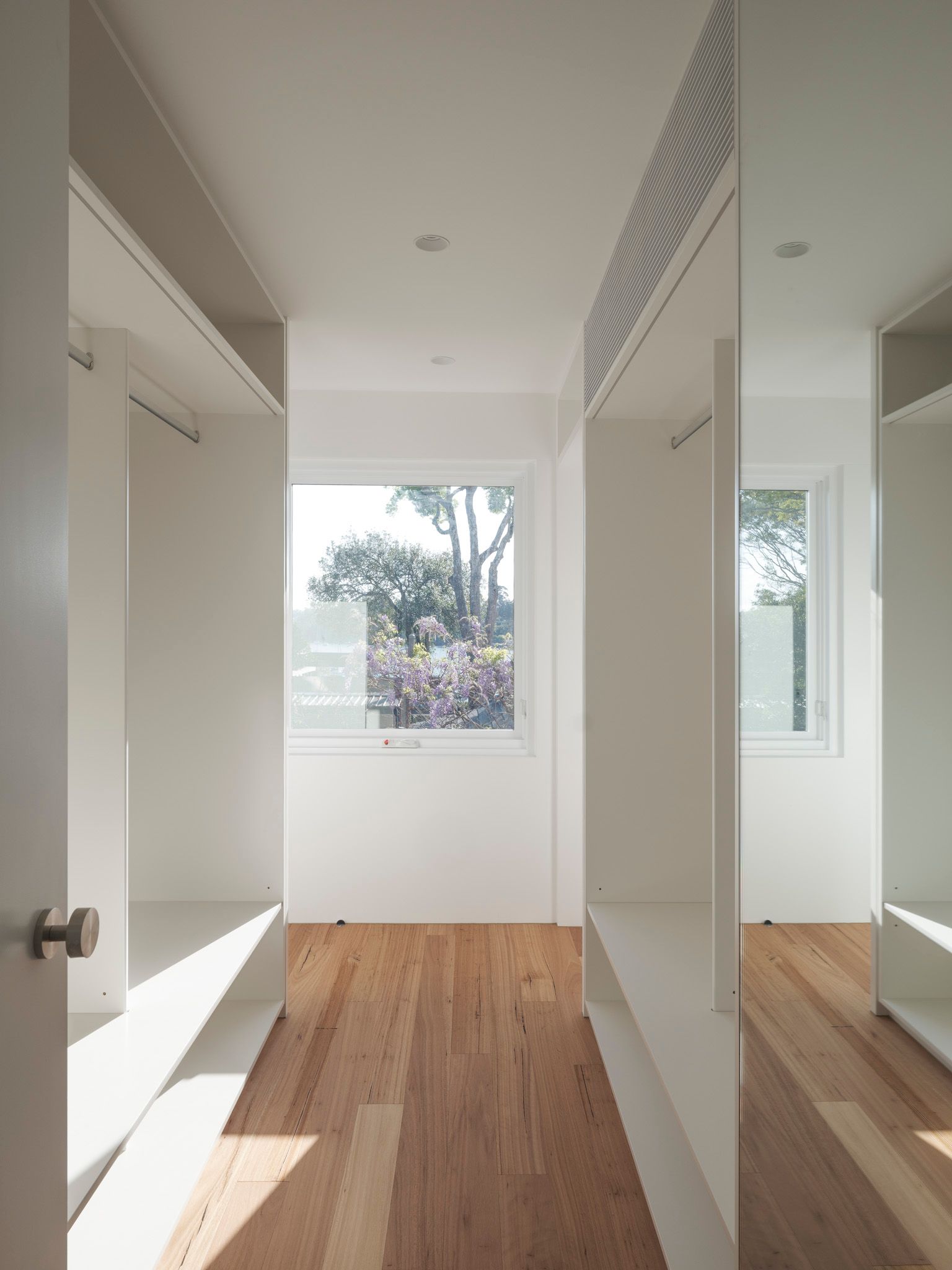 A walk in closet with wooden floors and white walls