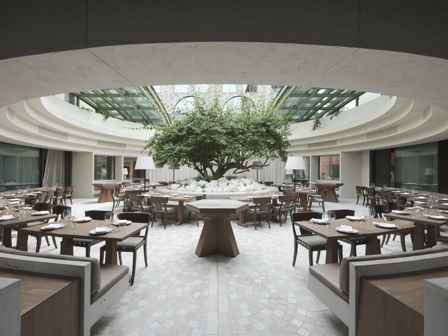 A restaurant with tables and chairs and a tree in the middle