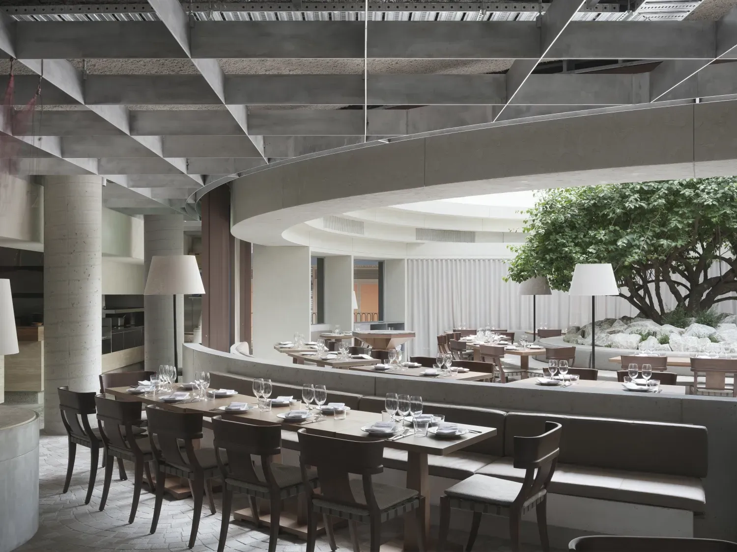 A restaurant with tables and chairs and a tree in the middle