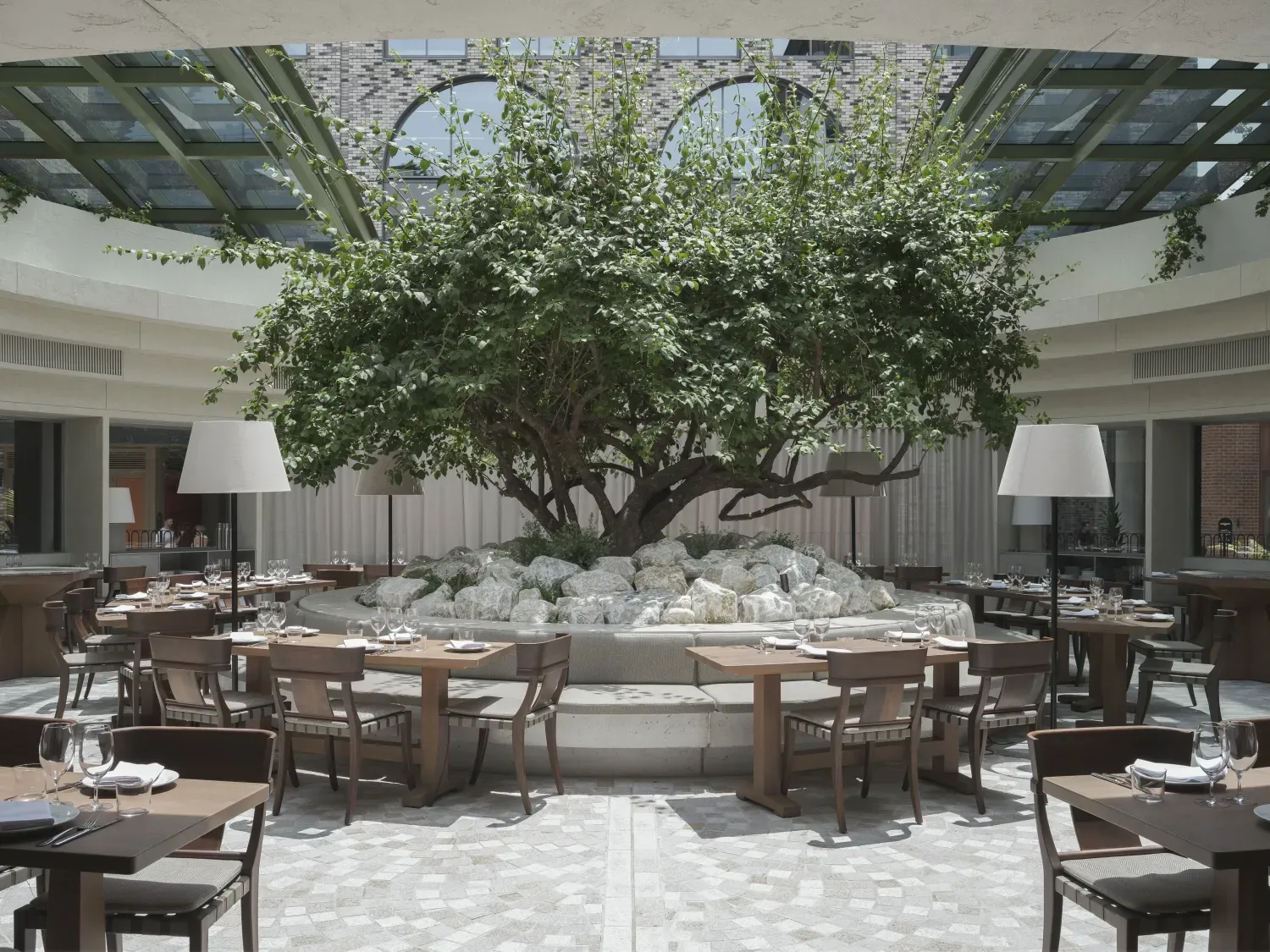 A restaurant with tables and chairs and a tree in the middle