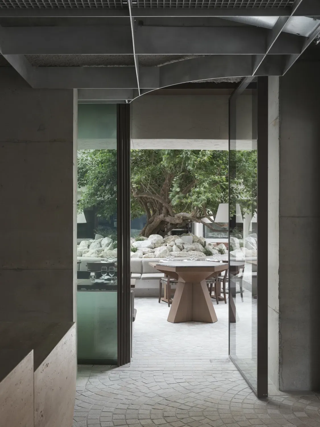 A room with a table and chairs in it and a tree in the background.