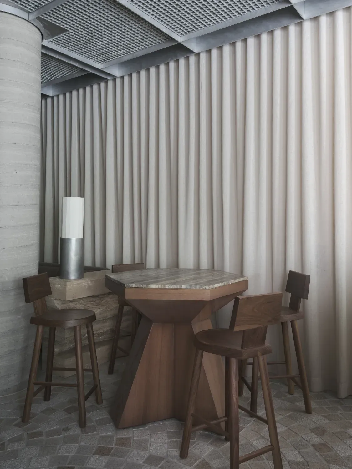 A room with a table and chairs in front of a wall.