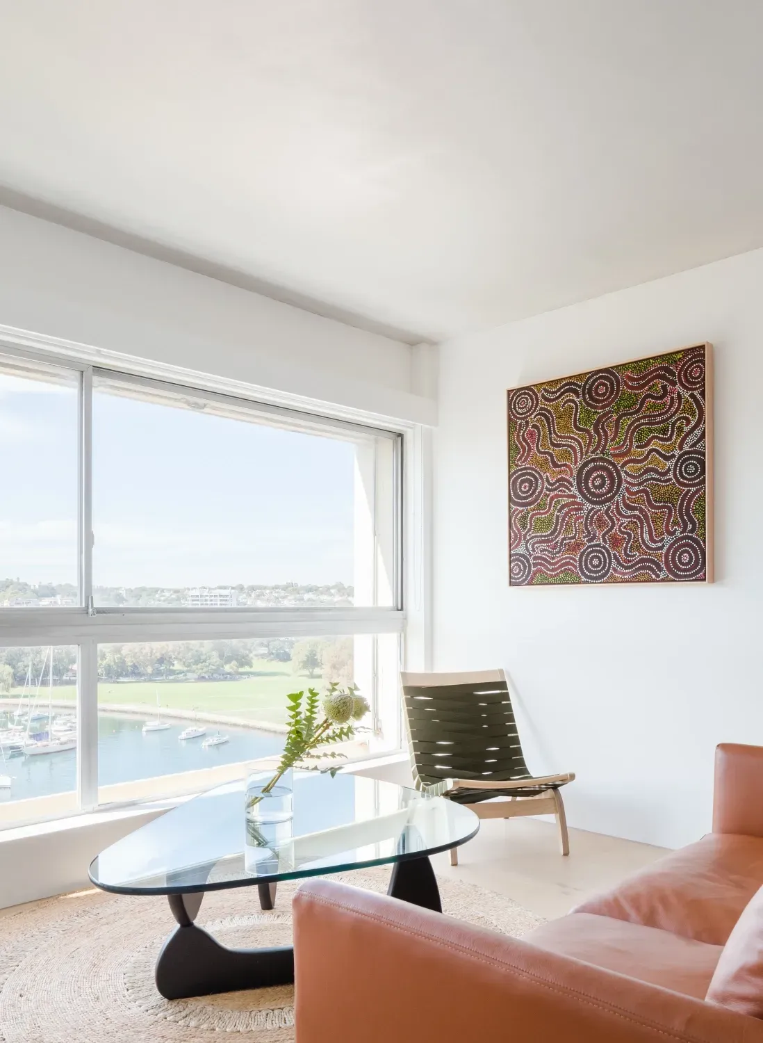 A living room with a couch , chair , coffee table and large window.