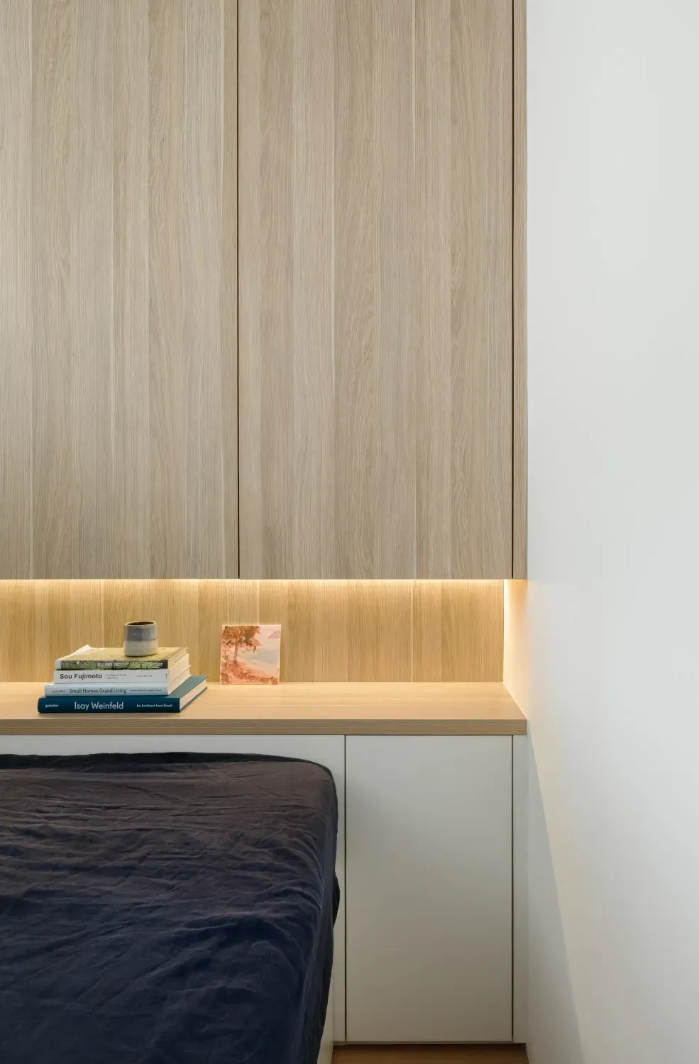 A bedroom with a bed and a desk with books on it.