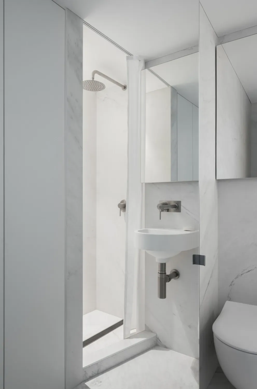 A bathroom with a sink , toilet , shower and mirror.