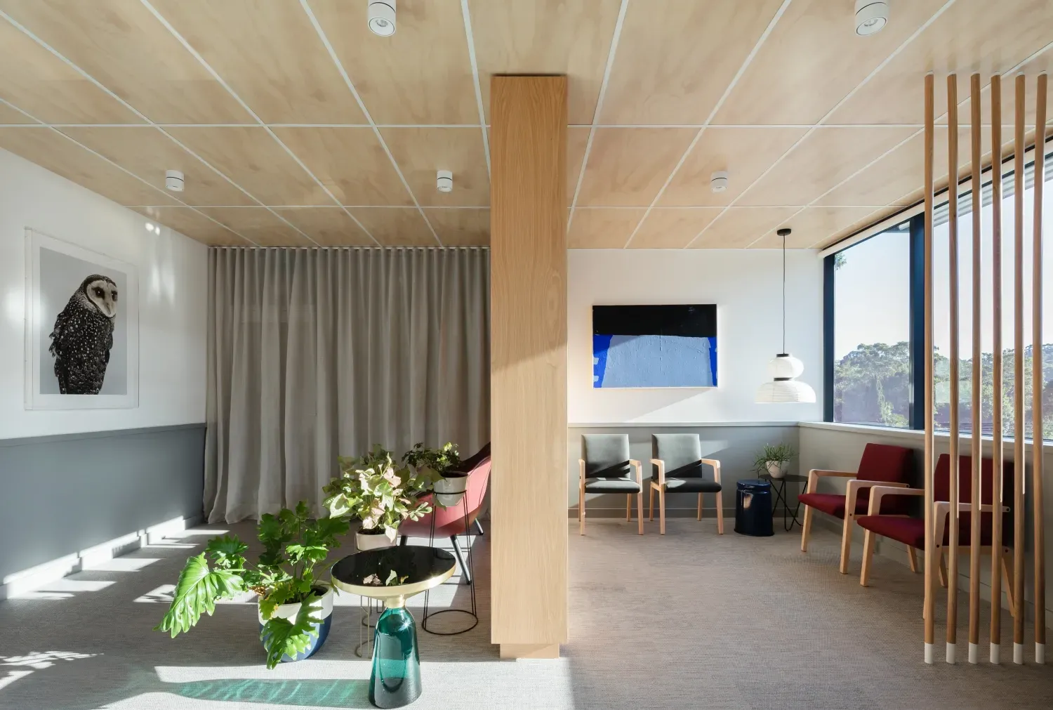 A waiting room with chairs , a table and a painting on the wall.