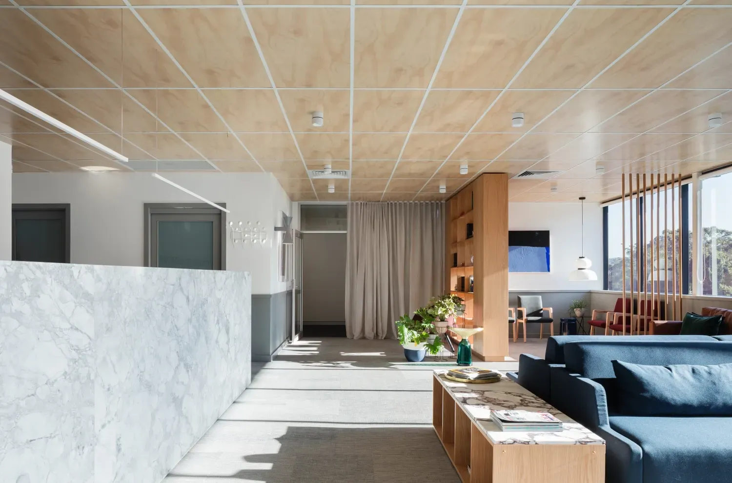 A living room with a blue couch and a wooden table.