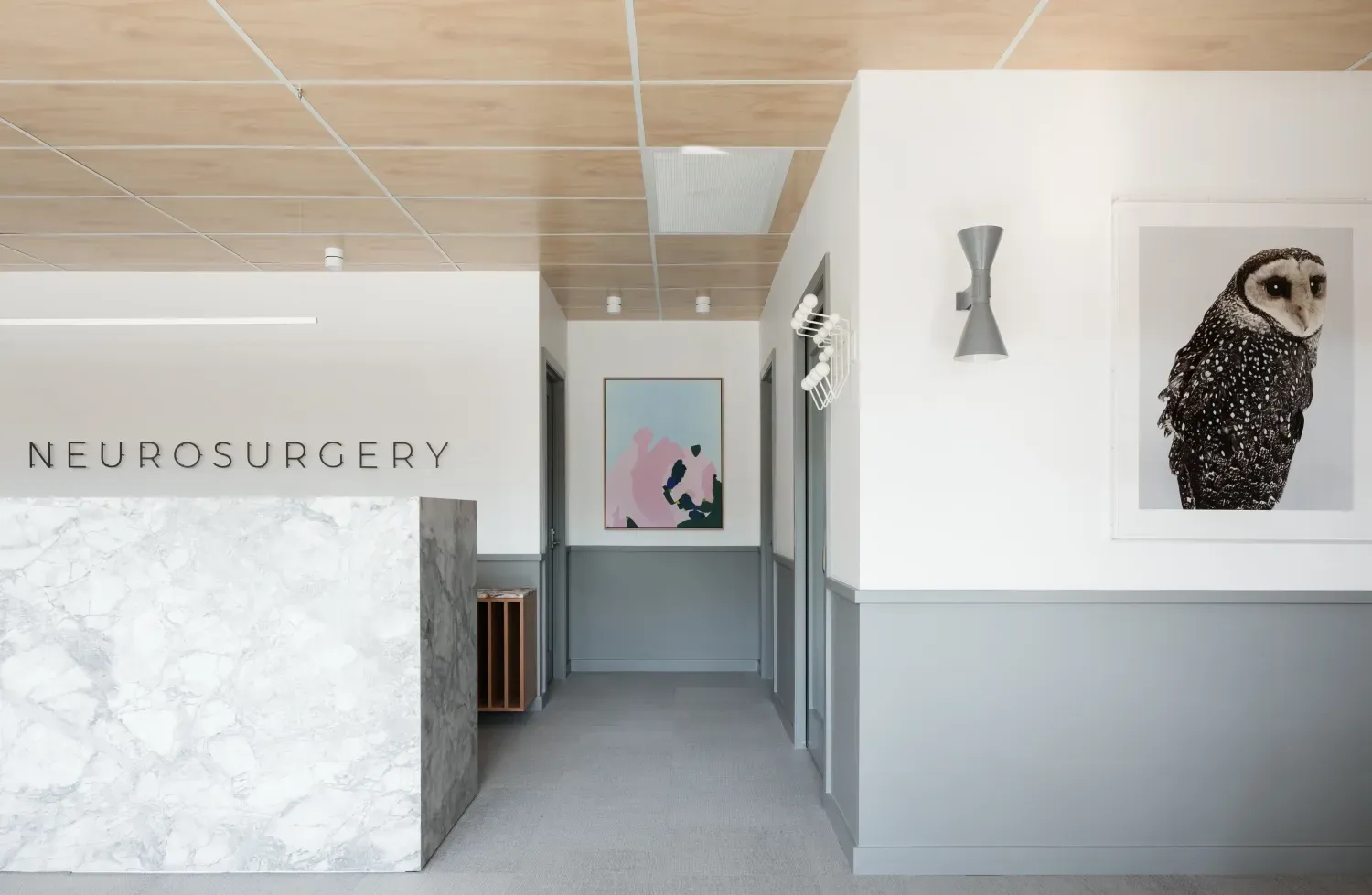 A hallway with a painting of an owl and a sign that says neurosurgery