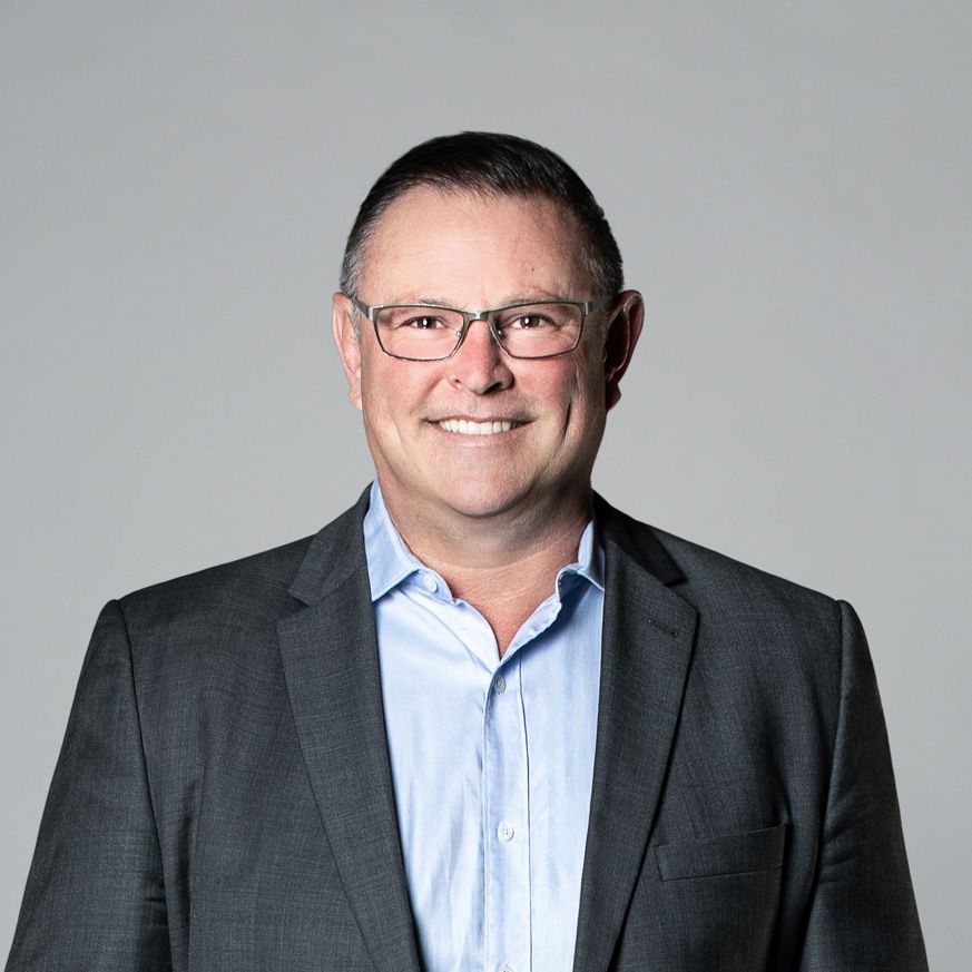 A man in a suit and glasses is smiling for the camera.
