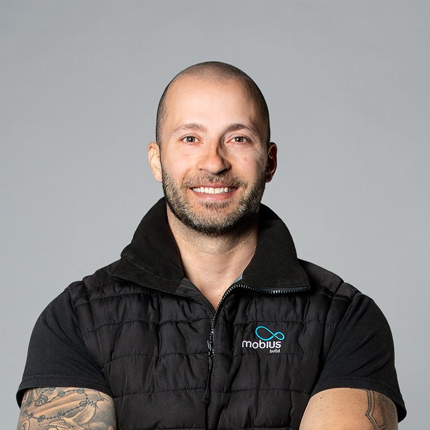 A man wearing a black vest with the word mobius on it