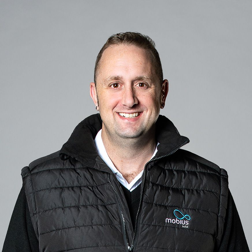 A man wearing a black vest with the word mobius on it