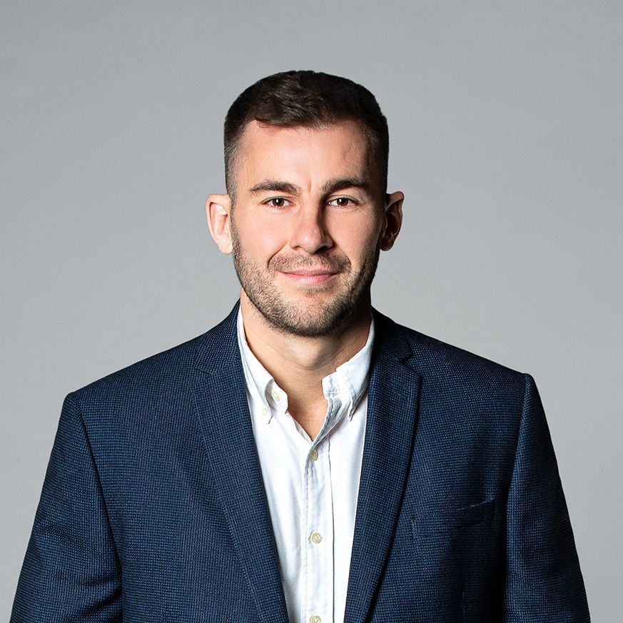 A man in a suit and white shirt is smiling for the camera.