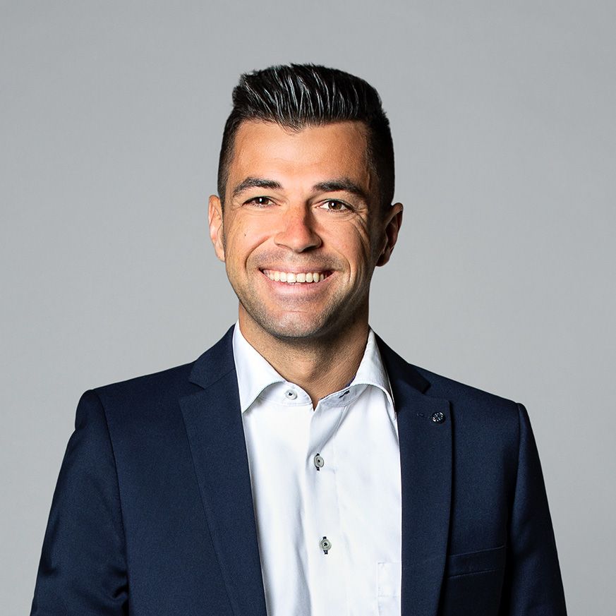 A man in a suit and white shirt is smiling for the camera.