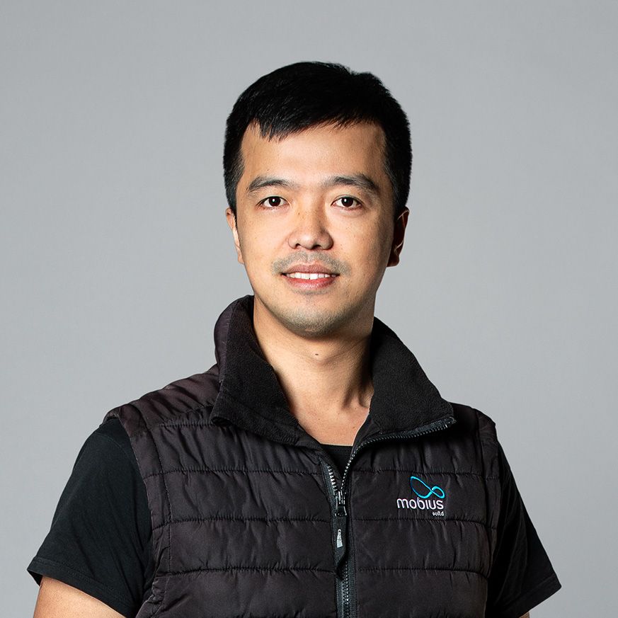 A man wearing a black vest and a black shirt is smiling for the camera.