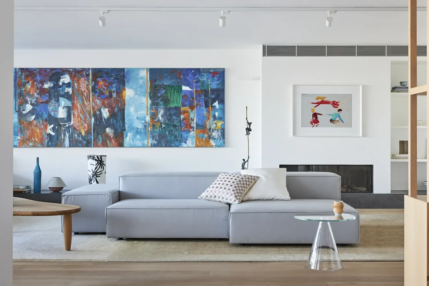 A living room with a couch , table , fireplace and paintings on the wall.