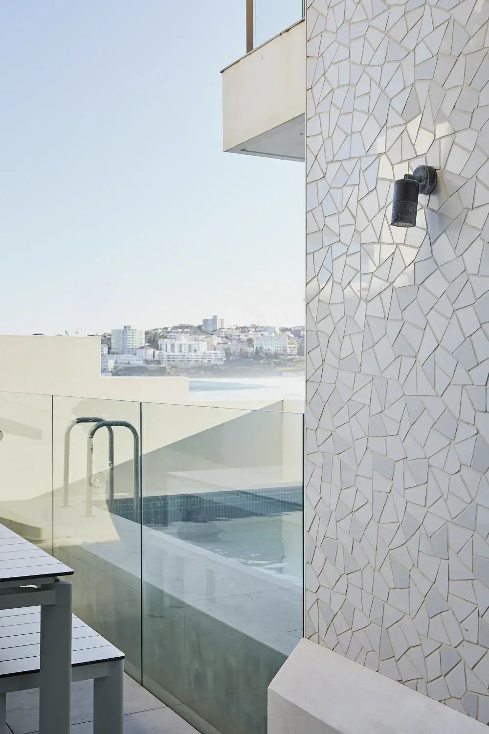 A balcony with a swimming pool and a table and chairs.