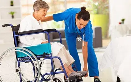 A nurse is helping an elderly woman in a wheelchair.