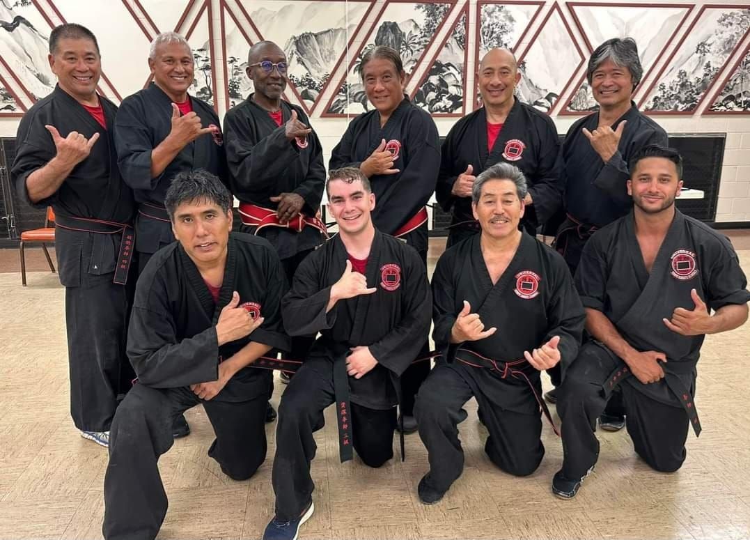 A group of men in black karate uniforms are posing for a picture.